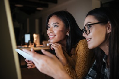 Happy businesswomen working late at night with office computer